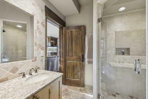 Full bath featuring vanity, a stall shower, recessed lighting, backsplash, and stone tile flooring