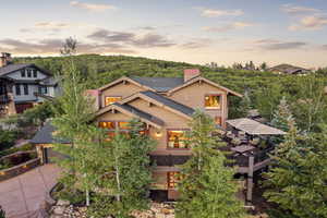 View of front of home with a chimney, concrete driveway, roof with shingles, and a forest view