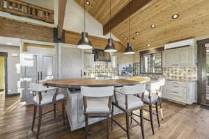 Kitchen featuring decorative light fixtures, butcher block countertops, a breakfast bar area, a center island, and decorative backsplash