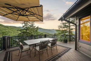 Deck at dusk featuring outdoor dining space, a mountain view, and a patio area