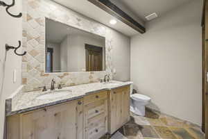 Full bath featuring backsplash, double vanity, dark stone finish flooring, and recessed lighting