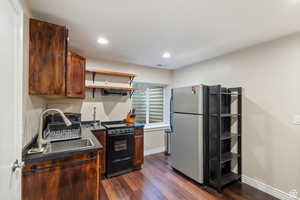 Kitchen with dark countertops, open shelves, black electric range, dark wood finished floors, and recessed lighting