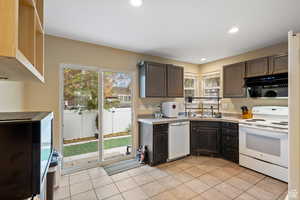Kitchen featuring white appliances, dark brown cabinets, light countertops, light tile patterned floors, and extractor fan