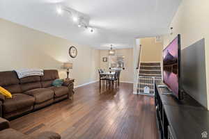 Living room featuring dark wood-style flooring, stairs, and track lighting