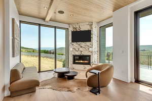 Living room with wood finished floors, a high end fireplace, a wood ceiling with exposed beams, and recessed lighting