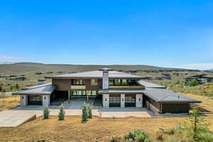 Rear view of property featuring a patio, a mountain view, driveway, and a metal roof