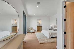 Bedroom featuring light wood-type flooring, ensuite bath, recessed lighting, and arched walkways