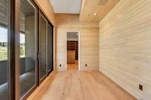 Spare room with wooden walls, light wood-type flooring, and recessed lighting
