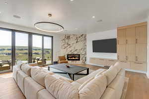 Living room featuring light wood finished floors, a fireplace, and recessed lighting