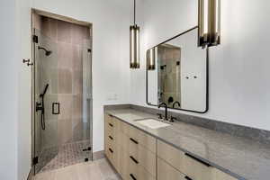 Full bath featuring a stall shower, vanity, and light tile patterned floors