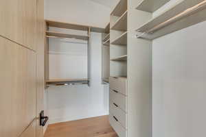 Walk in closet with light wood-style flooring