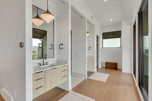Bathroom with light wood finished floors, vanity, and recessed lighting