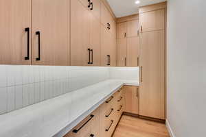 Kitchen with light brown cabinetry, light wood-type flooring, light stone counters, modern cabinets, and recessed lighting