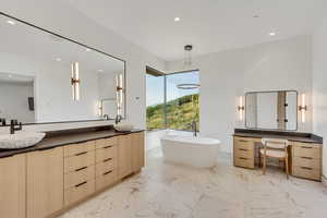 Bathroom featuring a freestanding tub, light marble finish floors, double vanity, and recessed lighting