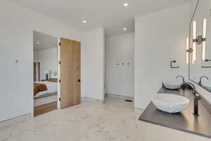 Ensuite bathroom featuring recessed lighting, light marble finish flooring, and double vanity