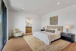 Bedroom featuring light wood-type flooring, recessed lighting, and connected bathroom