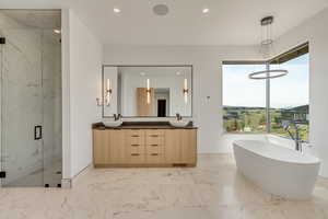Full bath featuring a freestanding bath, a marble finish shower, double vanity, recessed lighting, and light marble finish floors