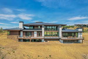 Rear view of property featuring a metal roof, a chimney, a standing seam roof, and a balcony