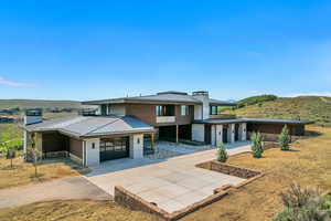 Prairie-style house featuring a metal roof, concrete driveway, and a garage