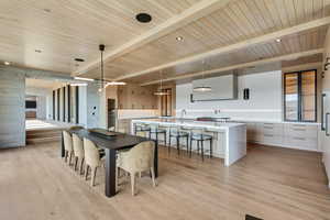 Dining space featuring light wood finished floors and a wood ceiling with exposed beams