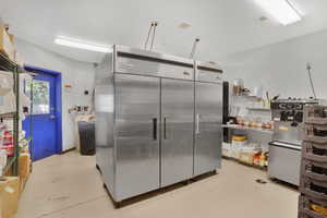 Kitchen with stainless steel fridge, finished concrete flooring, and open shelves