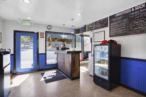 Welcome area with wainscoting, a textured ceiling, wooden walls, recessed lighting, and a bar
