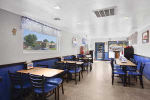Dining room with a wainscoted wall, a textured ceiling, wooden walls, and recessed lighting