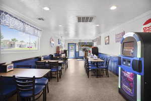 Dining space with a wainscoted wall, a textured ceiling, and recessed lighting