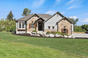 Craftsman house with stone siding, a front lawn, and board and batten siding