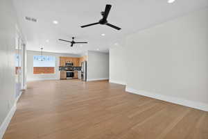 Unfurnished living room featuring a chandelier, light wood-type flooring, and recessed lighting