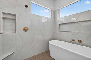Full bath with a freestanding tub, tile walls, and a tile shower