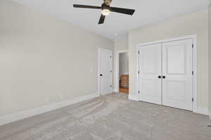 Unfurnished bedroom featuring carpet floors, a ceiling fan, and a closet