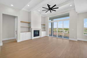 Unfurnished living room with light wood-style flooring, a glass covered fireplace, built in features, recessed lighting, and a ceiling fan