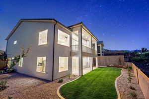 Property exterior at twilight with a balcony, stucco siding, and a fenced backyard