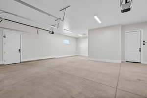 Garage featuring a garage door opener and baseboards