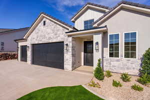 View of front of home with stone siding, a garage, and concrete driveway