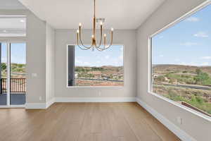 Unfurnished dining area with light wood-style floors, a chandelier, and healthy amount of natural light