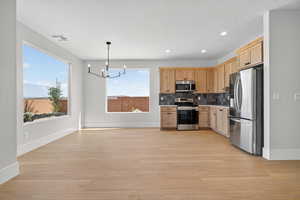 Kitchen featuring stainless steel appliances, a chandelier, light brown cabinets, hanging light fixtures, and recessed lighting