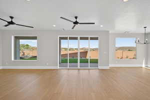 Unfurnished living room featuring plenty of natural light, a chandelier, light wood-style flooring, recessed lighting, and a ceiling fan