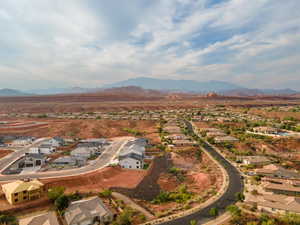 Aerial view of property and surrounding area featuring nearby suburban area and a mountain backdrop
