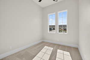 Carpeted spare room with baseboards and a ceiling fan