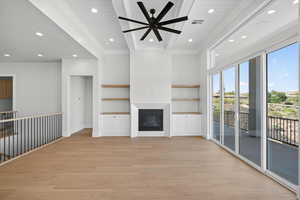 Unfurnished living room with a glass covered fireplace, recessed lighting, light wood finished floors, ornamental molding, and ceiling fan