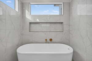 Bathroom featuring a freestanding tub and healthy amount of natural light