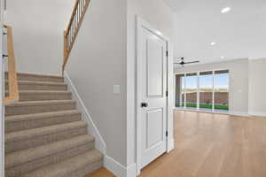 Stairs with wood finished floors, recessed lighting, and a ceiling fan