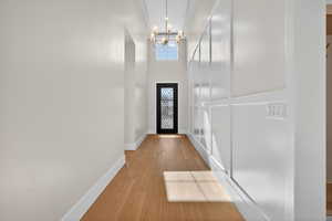 Entryway featuring wood finished floors, a chandelier, and a towering ceiling