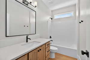 Bathroom with washtub / shower combination, vanity, and light wood-style flooring