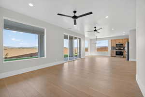 Unfurnished living room with a chandelier, a ceiling fan, light wood-style flooring, and recessed lighting