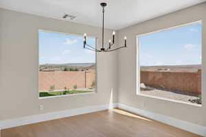Unfurnished dining area with a chandelier and light wood-style floors