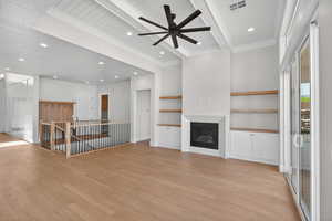 Unfurnished living room with light wood-type flooring, beam ceiling, recessed lighting, ceiling fan, and a glass covered fireplace