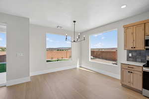Unfurnished dining area featuring light wood-style flooring, a chandelier, and a textured ceiling